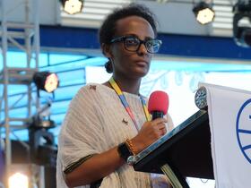 serious Habesha woman at podium with microphone